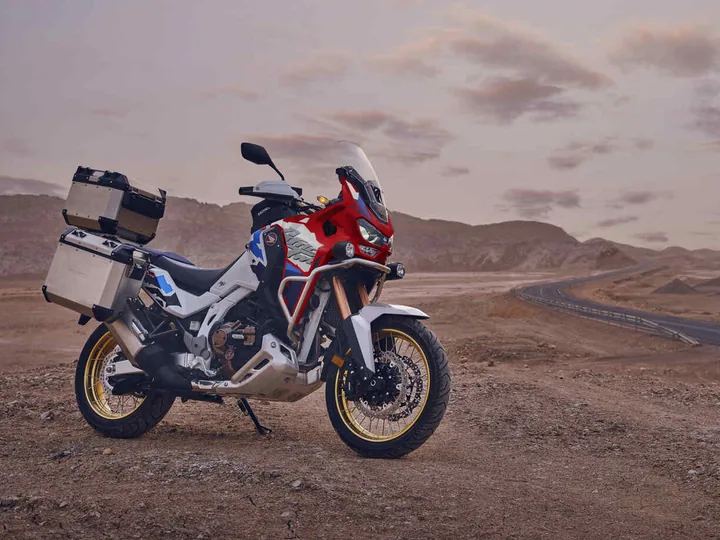 Honda Africa Twin équipée de valises, à l'arrêt devant une route sinueuse